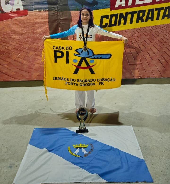 Boo capoeira posa com bandeiras da Casa do Piá, de Ponta Grossa e premiação.