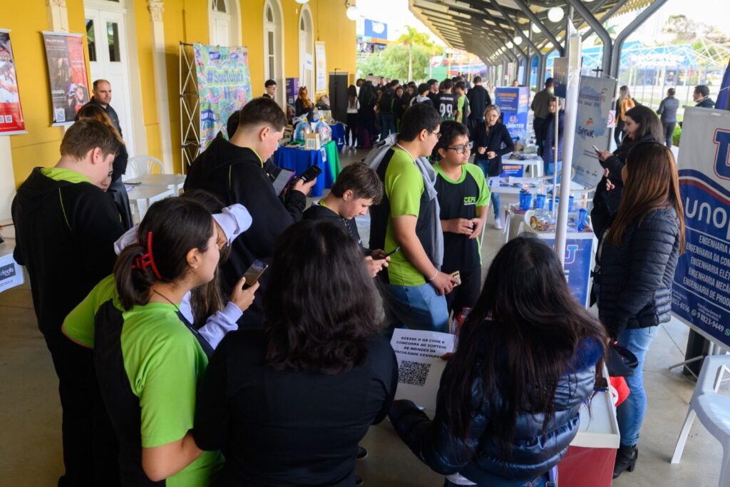 Adolescentes participam de oficina da Semana de Qualificação Profissional na Estação Saudade em Ponta Grossa analisando papeis e QR Codes