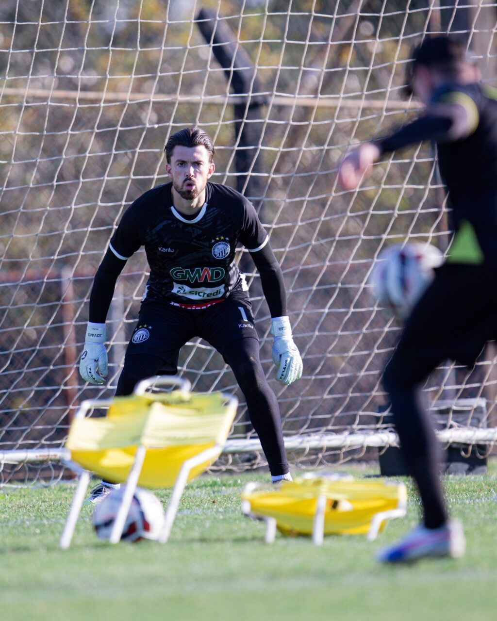 Goleiro Elias, do Operário, passa por treinamento com bolas e equipamentos de preparação no gramado.
