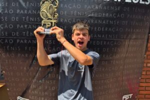 tenista miguel lima exibe seu troféu com fundo da galeria dos campeões