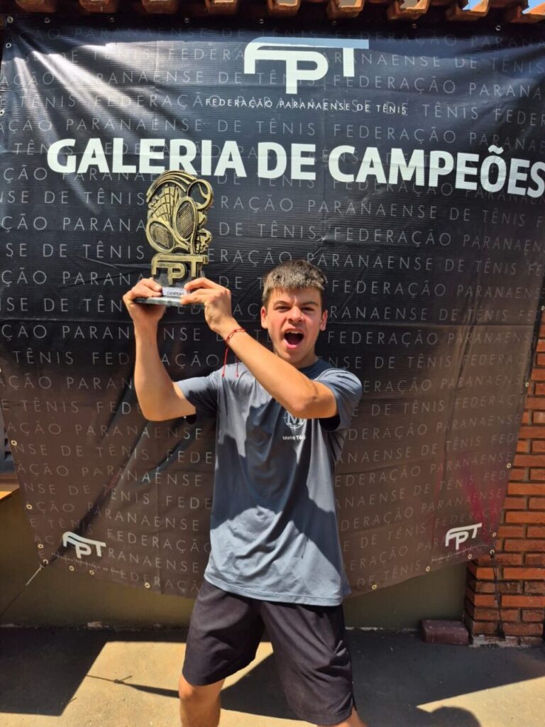 tenista miguel lima exibe seu troféu com fundo da galeria dos campeões