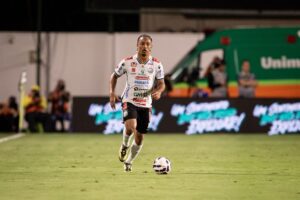 Atleta do Operário vestindo uniforme preto e branco conduzindo a bola