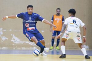 Jogador da ACGF em azul dribla adversário em foto que ilustra pauta dos Jogos Abertos do Paraná