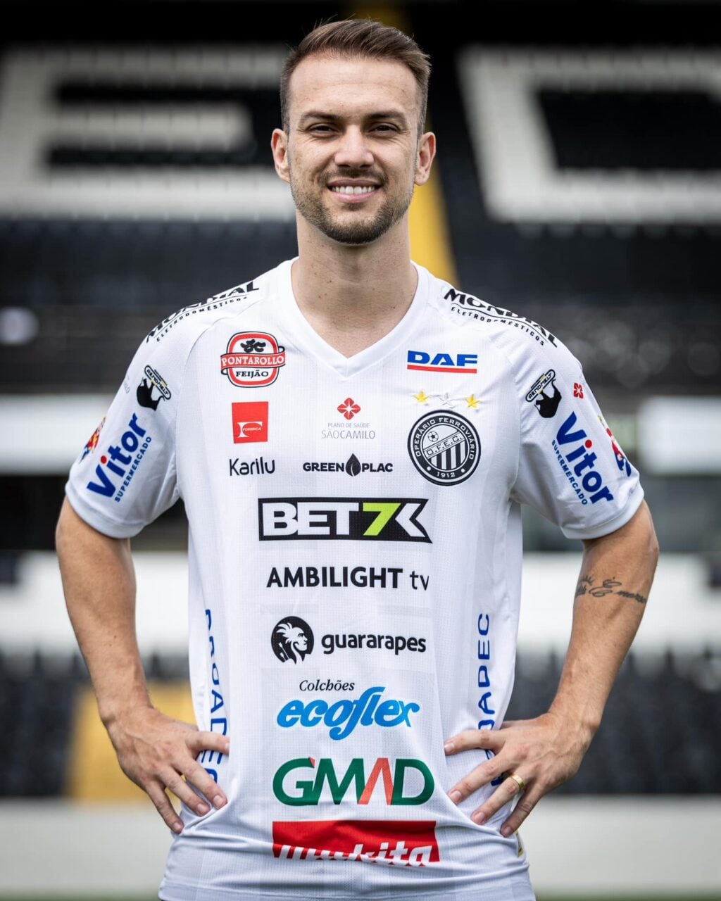 Jhemerson posa coma camisa do Operário Ferroviário tendo ao fundo a arquibancada.