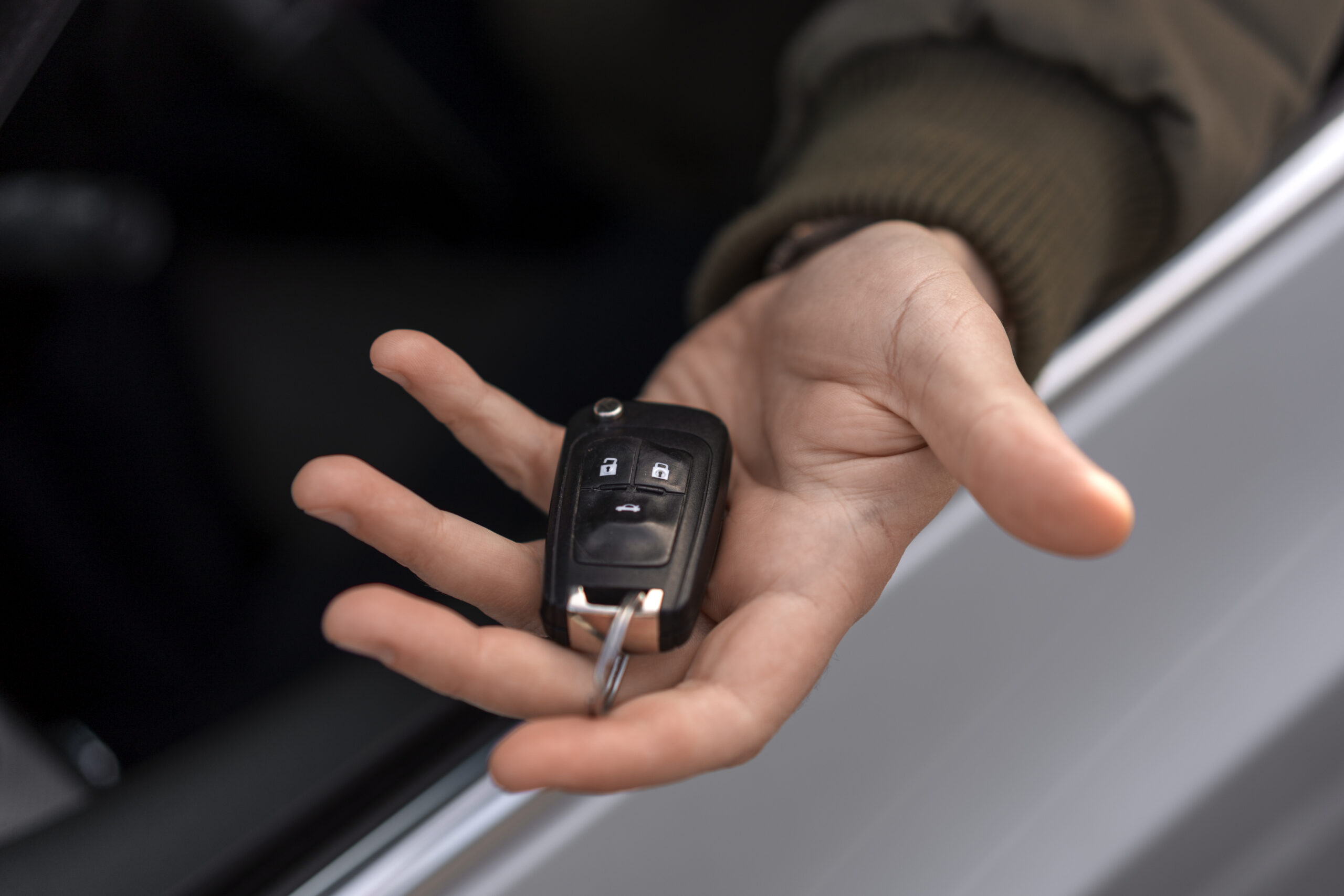 Palma da mão virada para cima, segurando a chave de um carro. 