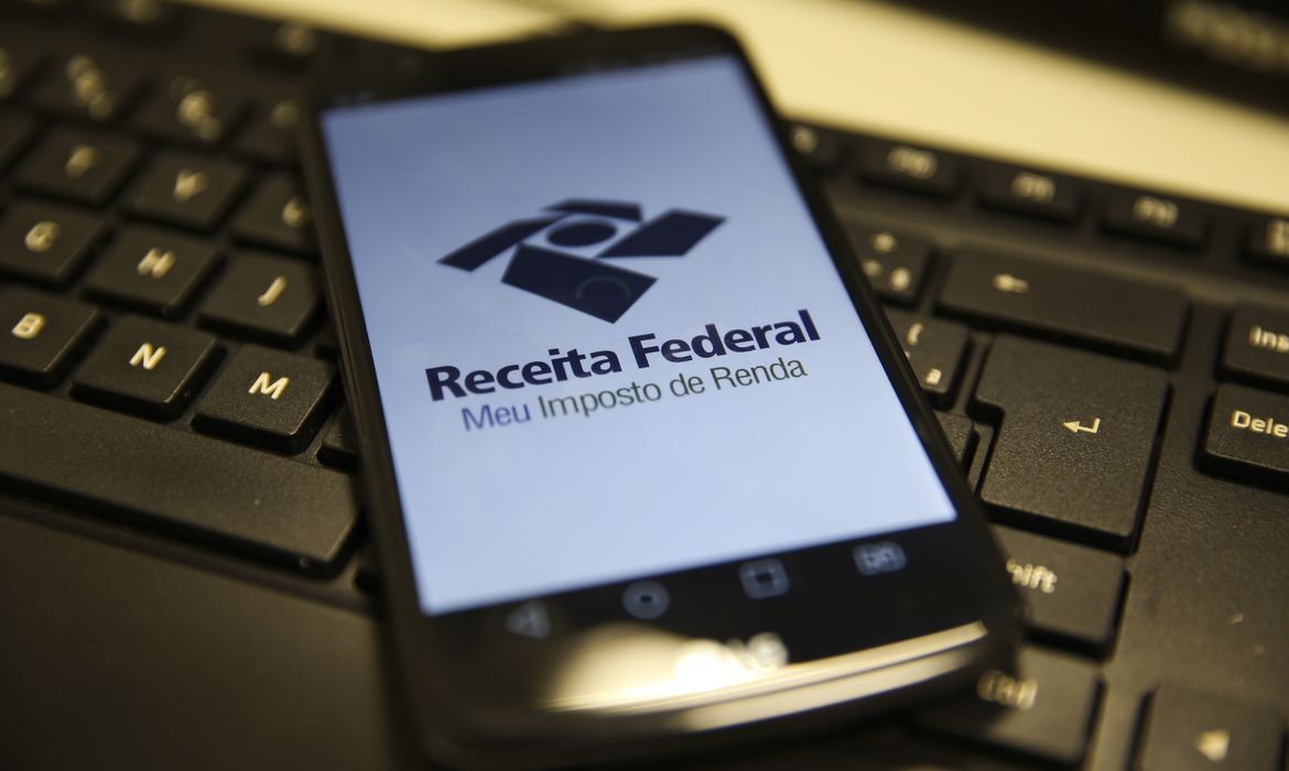 Celular com logo da Receita Federal relacionado à restituição do IRPF