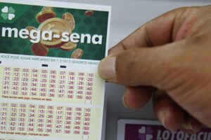 Mão segura bilhete de aposta da Mega Sena