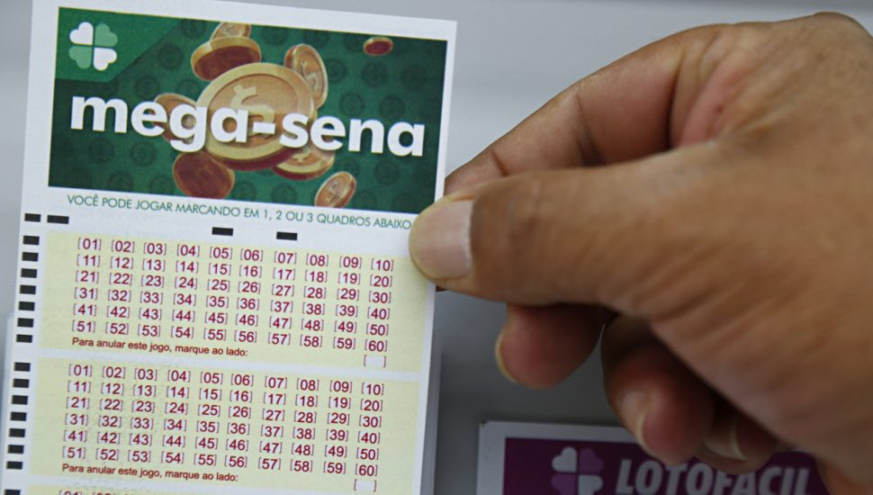 Mão segura bilhete de aposta da Mega Sena