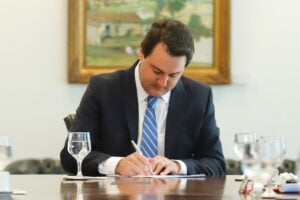 Ratinho Junior em seu gabinete de Governador do Paraná, assinando papel