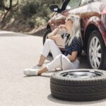 sad-young-woman-sitting-near-broken-down-car-road