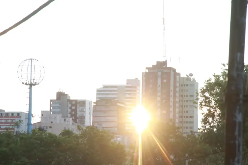 Sol aparecendo entre dois prédios em Ponta Grossa ilustra a previsão do tempo