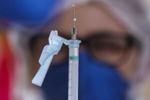 Mulher segura a agulha com a dose da vacina contra a covid-19.