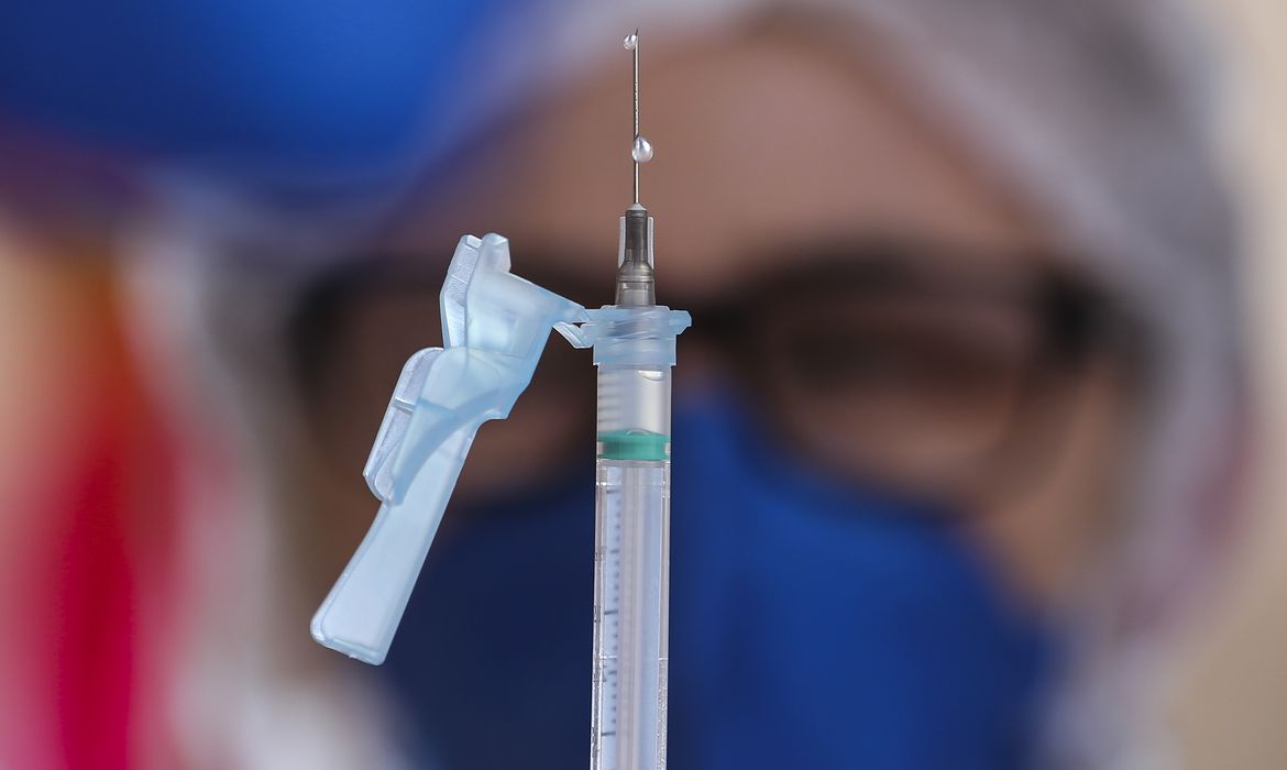Mulher segura a agulha com a dose da vacina contra a covid-19.