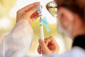 enfermeira segurando uma agulha com dose da vacina contra a covid-19