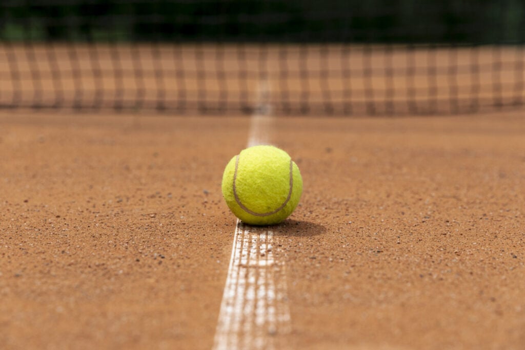 Bola de tênis em quadra de saibro ilustra o Frísia Open de Tênis