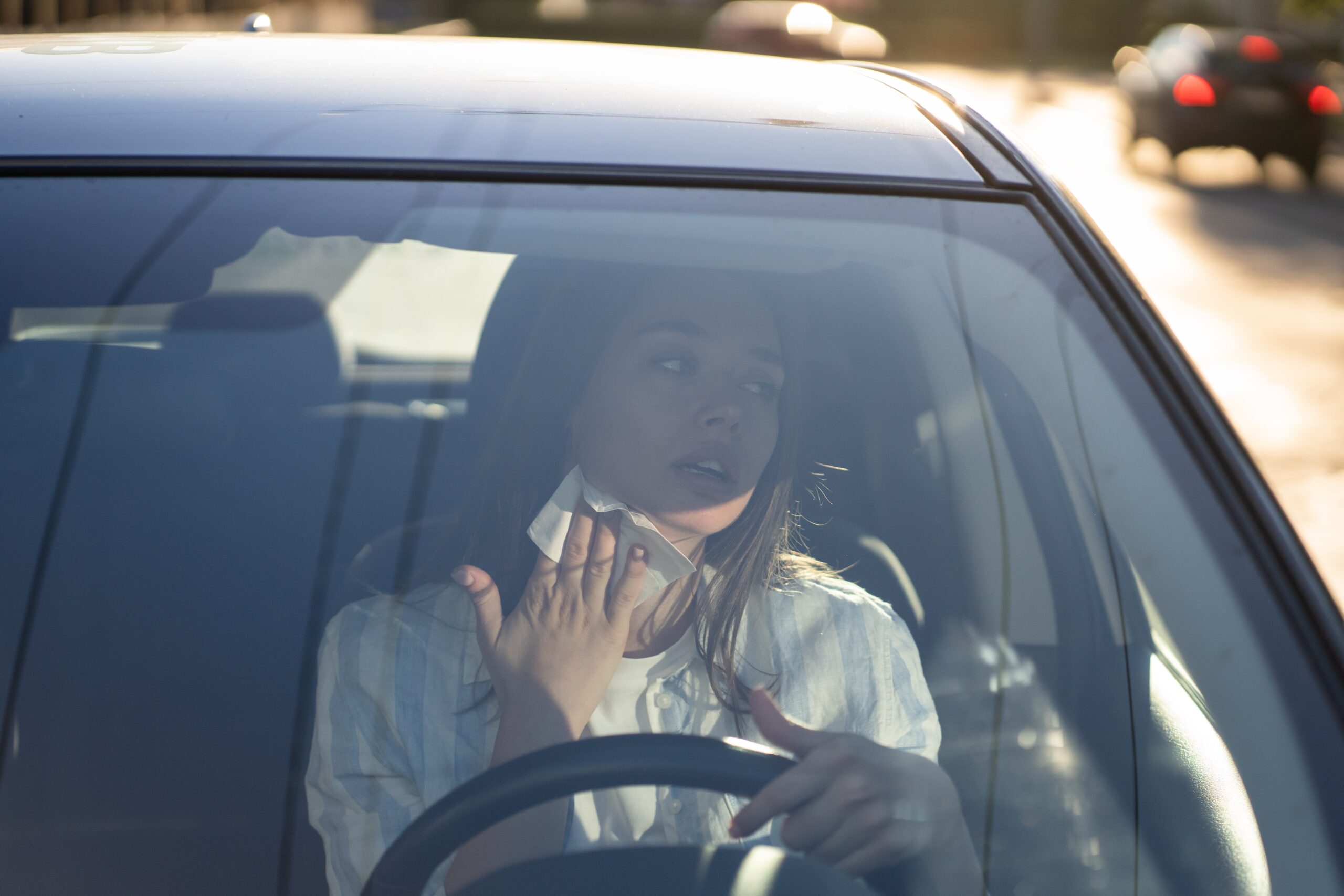 Mulher passando calor no interior de carro, usa lenço para enxugar o suor do pescoço