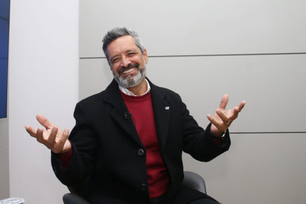 Pastor Moisés Faria em entrevista no estúdio do Diário dos Campos, sorrindo e com as mãos elevadas