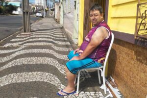 Paulo César Galvão, 55 anos, sentado em uma cadeira na calçada em frente à residência