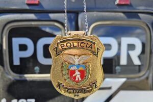 Distintivo da Polícia Civil do Paraná, com uma viatura em segundo plano