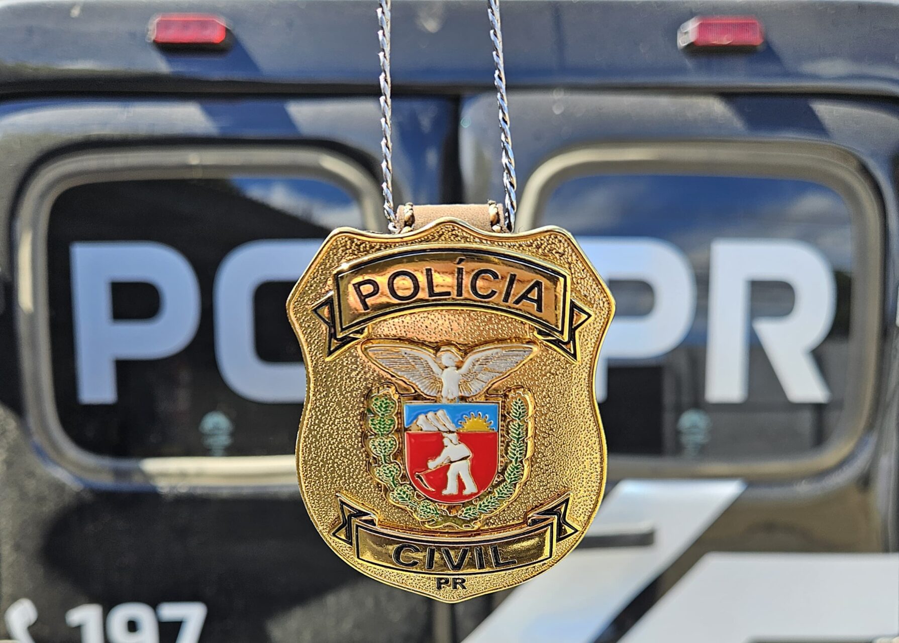 Distintivo da Polícia Civil do Paraná, com uma viatura em segundo plano