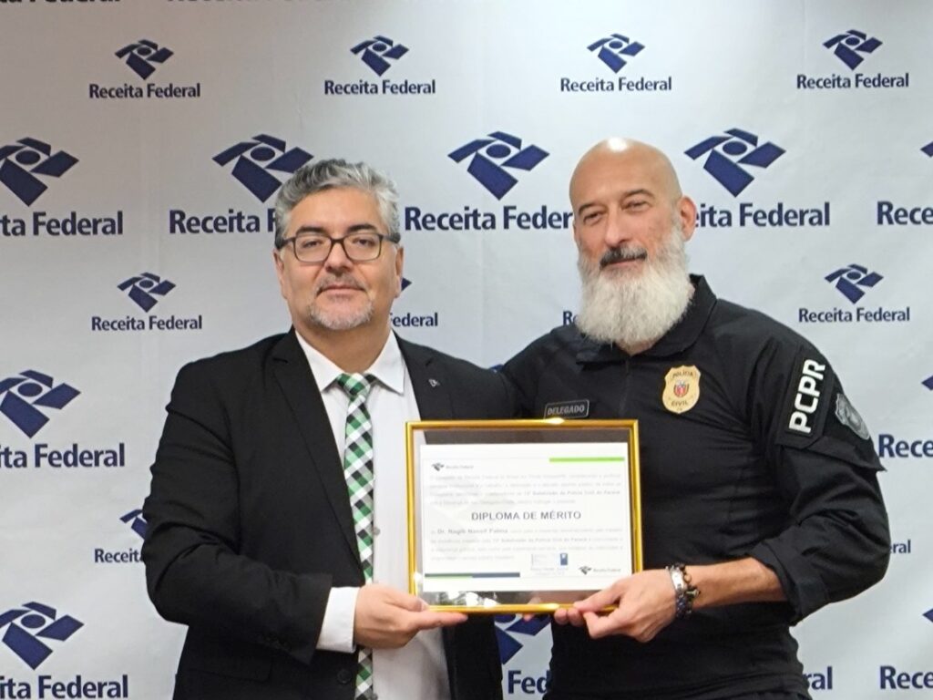 Delegado Dr. Remy Deiab Junior e Delegado Dr. Nagib Palma segurando diploma de mérito na Delegacia da Receita Federal de Ponta Grossa
