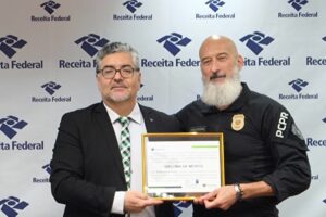 Delegado Dr. Remy Deiab Junior e Delegado Dr. Nagib Palma segurando diploma de mérito na Delegacia da Receita Federal de Ponta Grossa