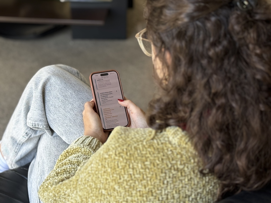 Estudante de costas visualiza tela de celular