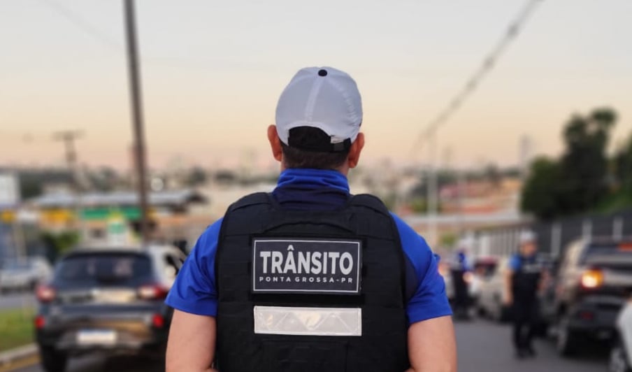 Agente de trânsito de costas observando o movimento da rua