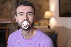 Spoiled grown up man licking a pacifier to control a tantrum.