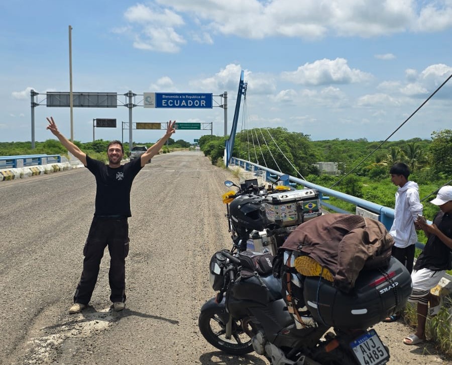 Luiz Petal posa ao lado de sua moto, diante da placa de chegada ao Equador