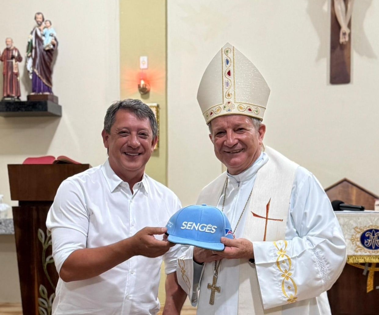 Prefeito de Sengés Gerson Nunes ao lado de Dom Mário, novo Arcebispo de Aparecida, segurando um boné com o nome do município dos Campos Gerais