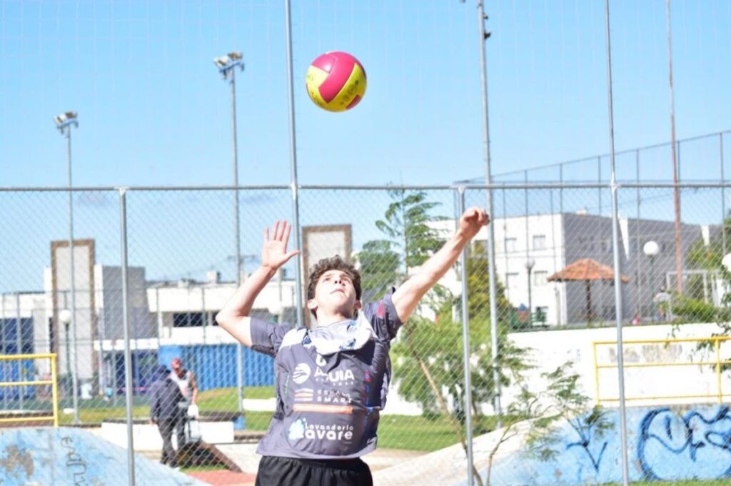 Homem pulando para acertar a bola de volei que está no ar.