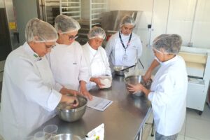Cinco pessoas produzindo alimentos em uma cozinha
