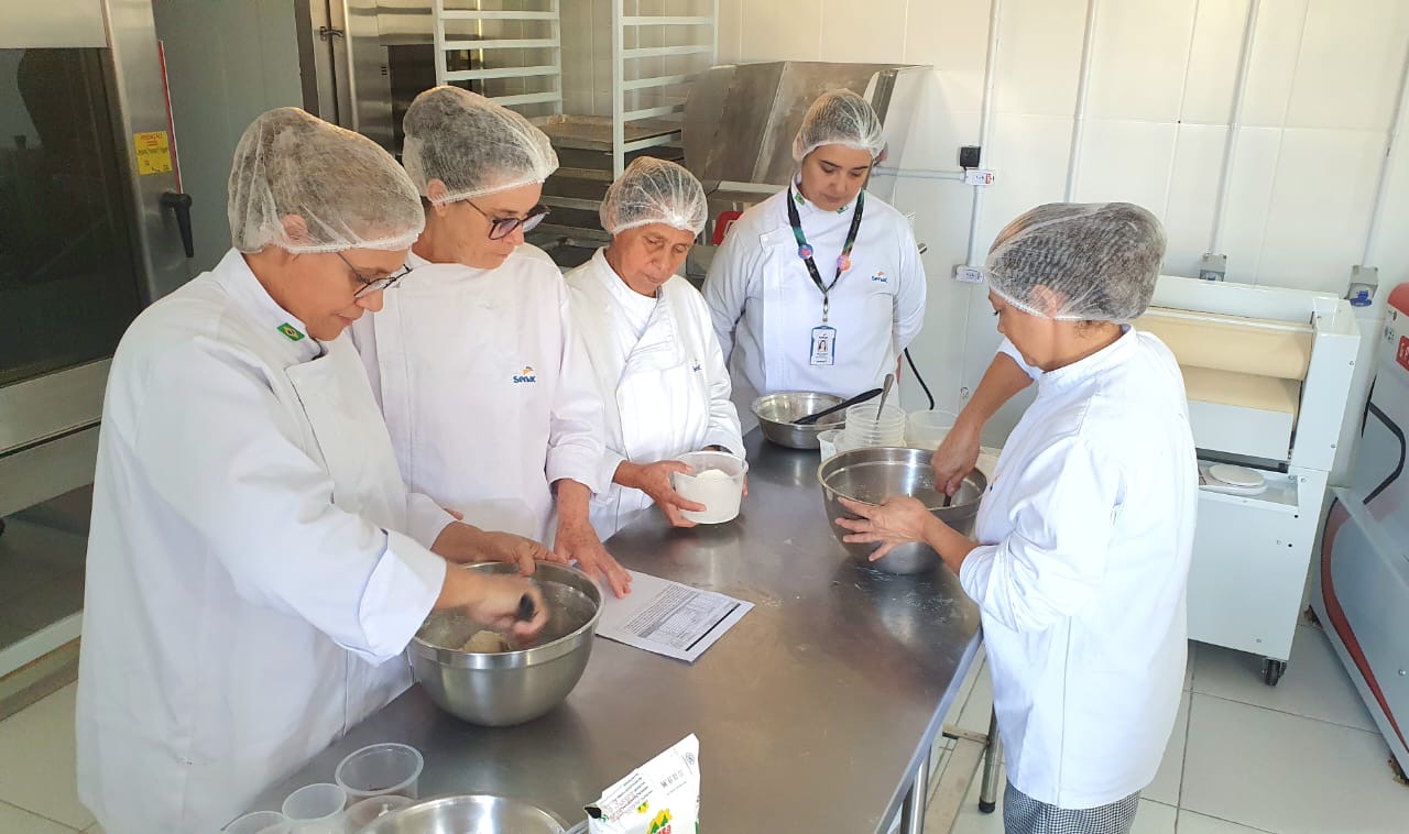 Cinco pessoas produzindo alimentos em uma cozinha