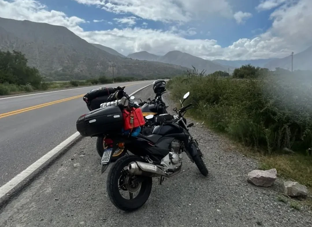Motocicletas paradas à beira da rodovia na Argentina, tendo ao fundo a imagem de montanhas