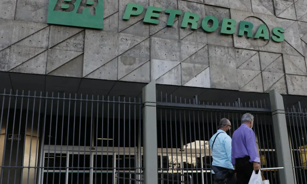 Duas pessoas passando na frente do prédio da petrobras
