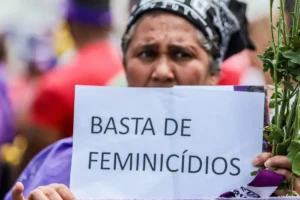 Mulher segura cartaz com a frase "Basta de feminicídios"