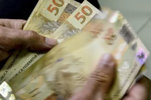 Pessoa segurando várias notas de 50 reais