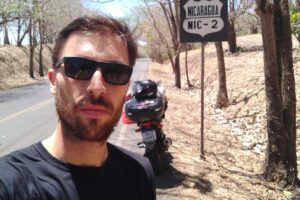 Professor Fred Petla em selfie com uma placa de Nicarágua, ao lado de sua moto