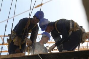 Operários trabalhando em construção civil e fazendo uso de EPIs