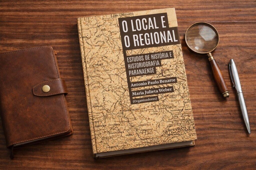 Livro O Local e o Regional sobre mesa de madeira