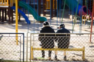 pessoas agasalhadas, sentadas em um banco de praça em Ponta Grossa