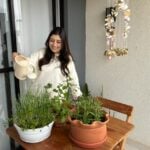 Mulher regando plantas em uma pequena horta em apartamento