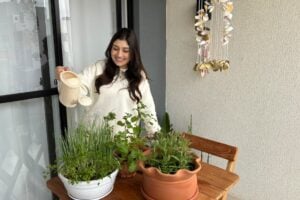 Mulher regando plantas em uma pequena horta em apartamento