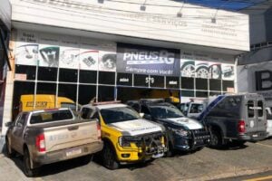 Fachada da Simão Pneus, empresa de Ponta Grossa, com veículos estacionados em frente
