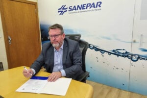 Wilson Bley Lipski, CEO da Sanepar, assinando documento em uma mesa