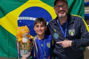 Bernardo Tozetto segurando o troféu de Campeão da Copa Internacional Kids com a Seleção Brasileira Sub-12 de Futsal, junto de seu treinador Maikom Parpinelli