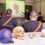 Boné do Corpo de Bombeiros sob uma mesa ao lado de um crânio