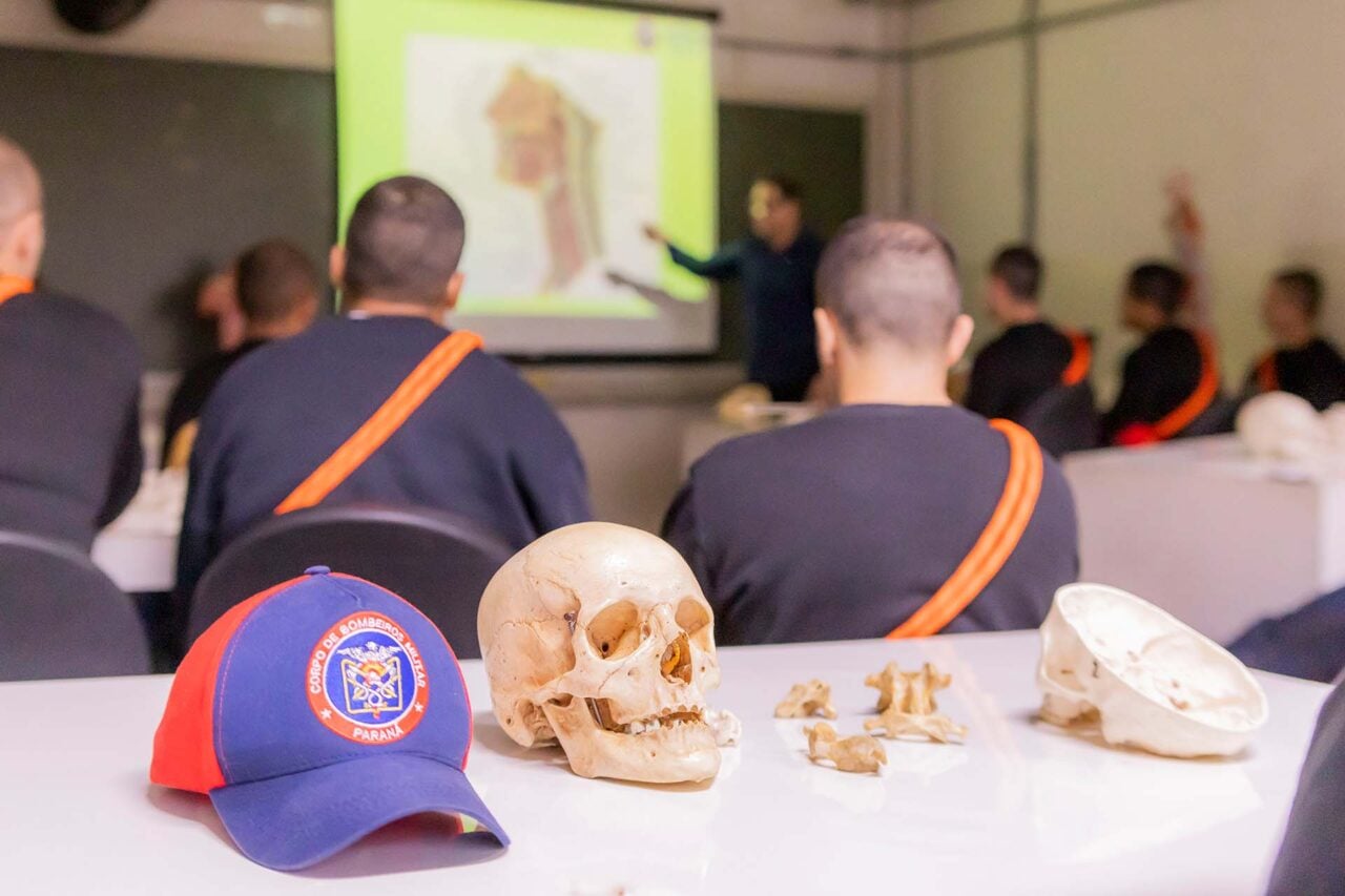 Boné do Corpo de Bombeiros sob uma mesa ao lado de um crânio