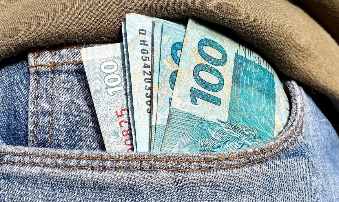 Foto de notas de R$ 100 em um bolso de calça